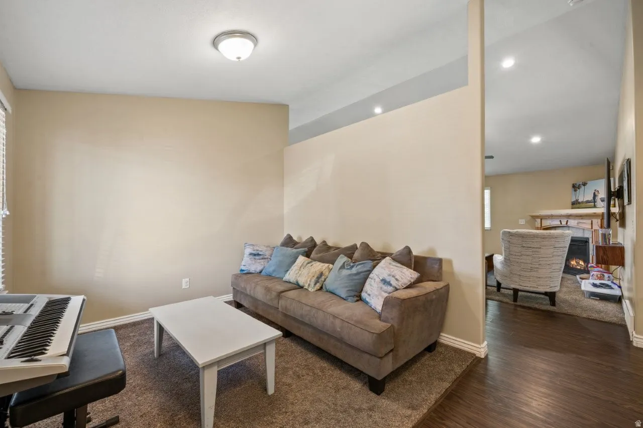 Carpeted living area featuring neutral wall tones, baseboard molding, and a partial wall divider