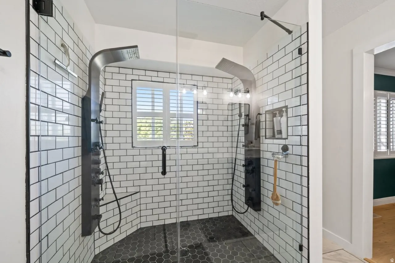 Glass-enclosed shower with white subway tile walls and dark grout