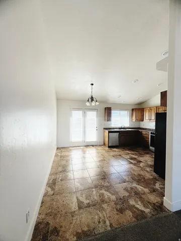 Spacious kitchen and dining area featuring large format tile flooring, wood cabinetry, and a full suite of appliances including a black range and refrigerator
