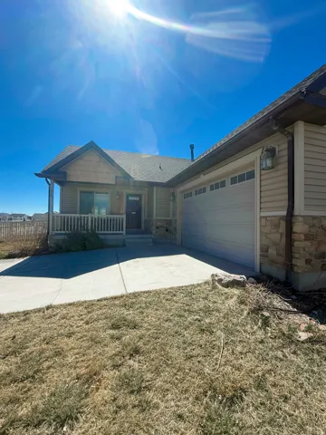 Exterior featuring beige siding, stone accents, and a covered porch with white railing