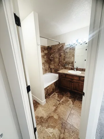Bathroom featuring a tiled shower surround, soaking tub, and a wood-finish vanity with a built-in sink