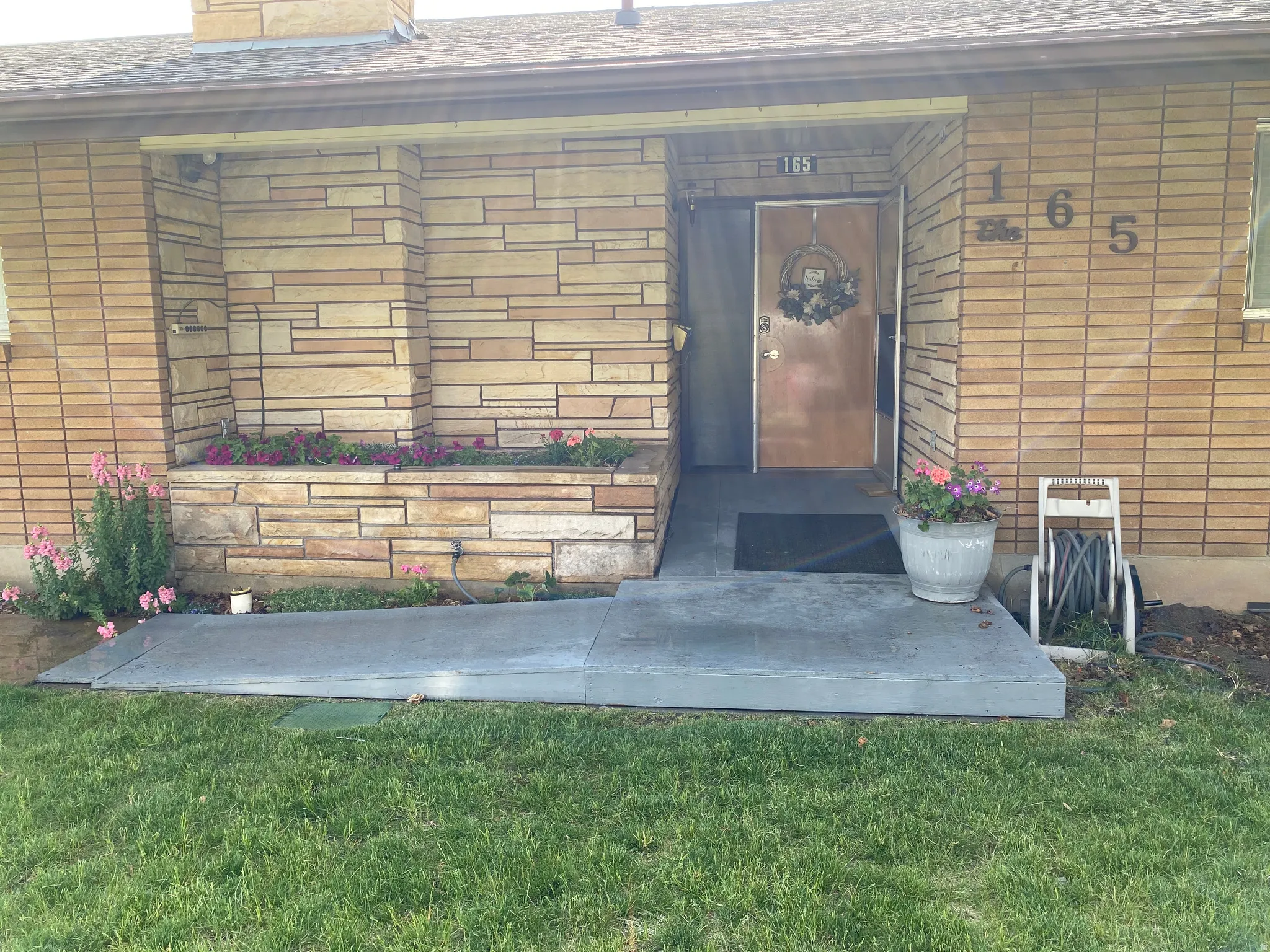 Front exterior featuring a covered entry, stone veneer accents, and a concrete ramp