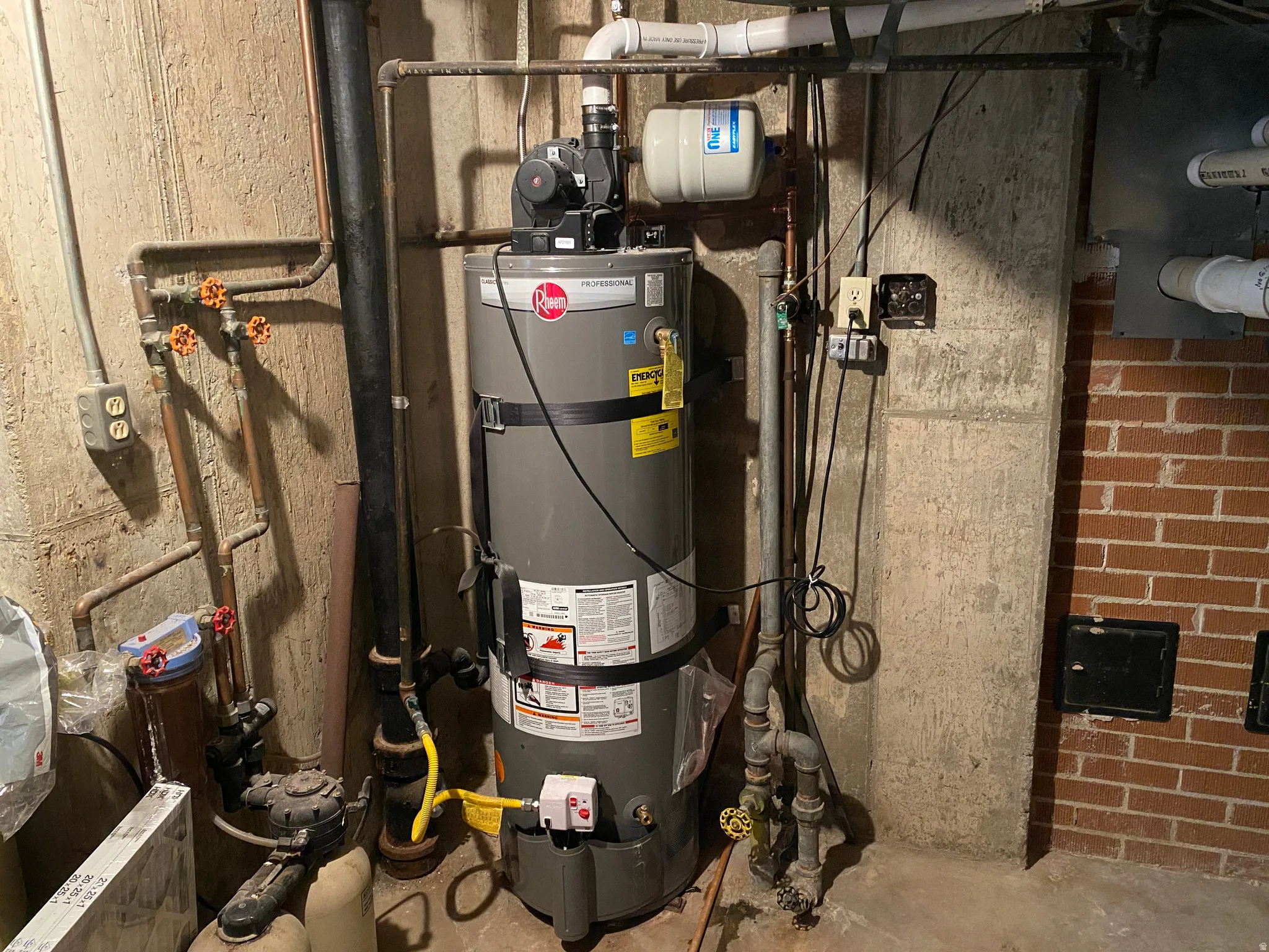 Water heater system featuring a Rheem tank, associated plumbing, and an expansion tank