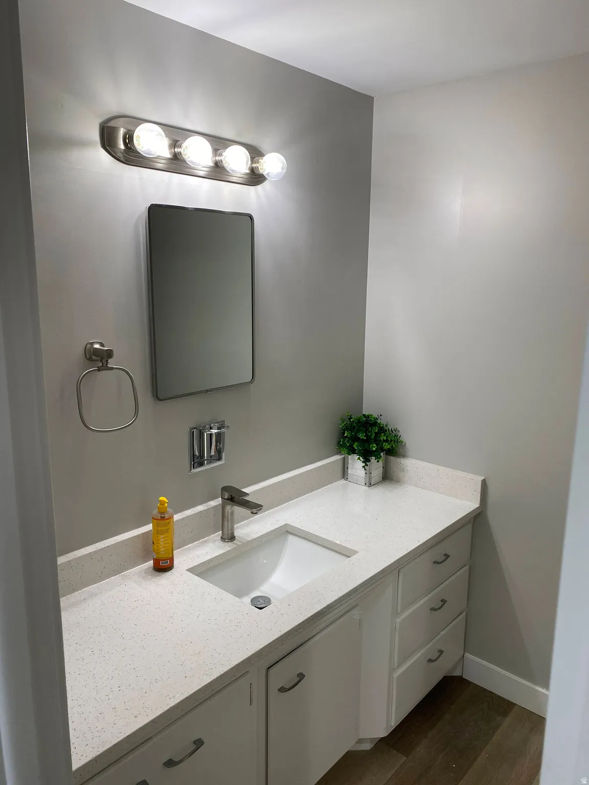 Bathroom vanity with a white rectangular undermount sink, a chrome single-handle faucet, and white cabinetry