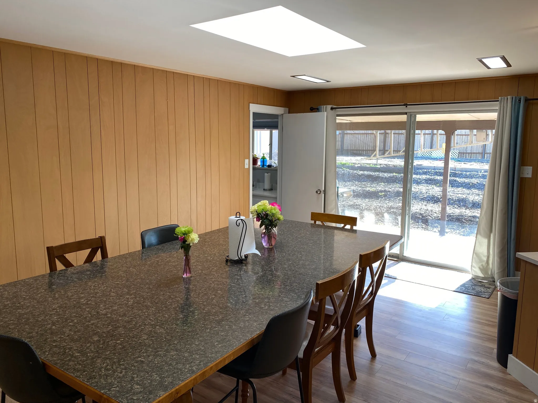 Dining area featuring wood-finish flooring, wood paneling, and a skylight