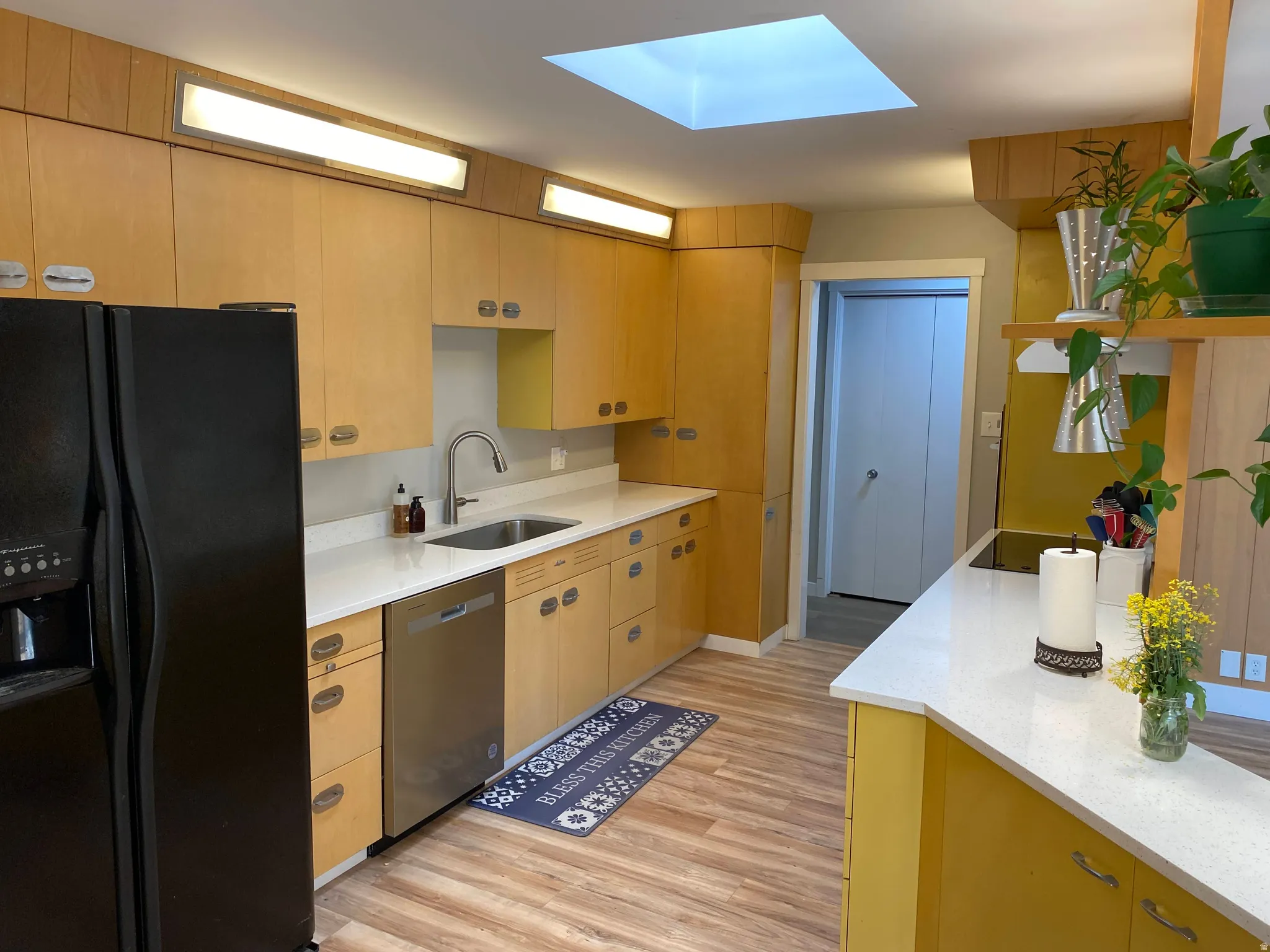 Kitchen featuring light wood-finish cabinetry, white countertops, and wood-finish flooring