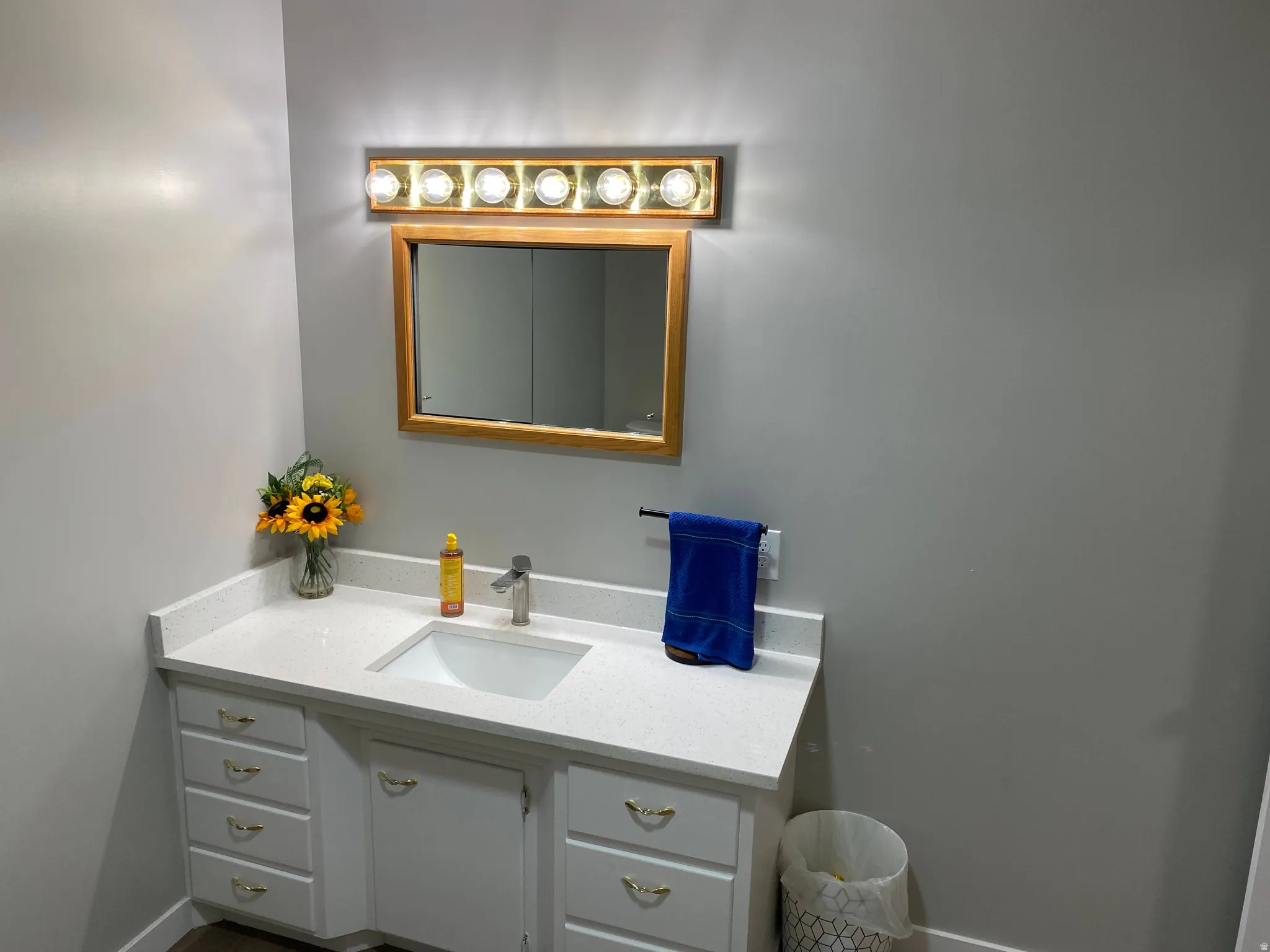 Vanity with a white countertop featuring an integrated sink and brushed nickel faucet