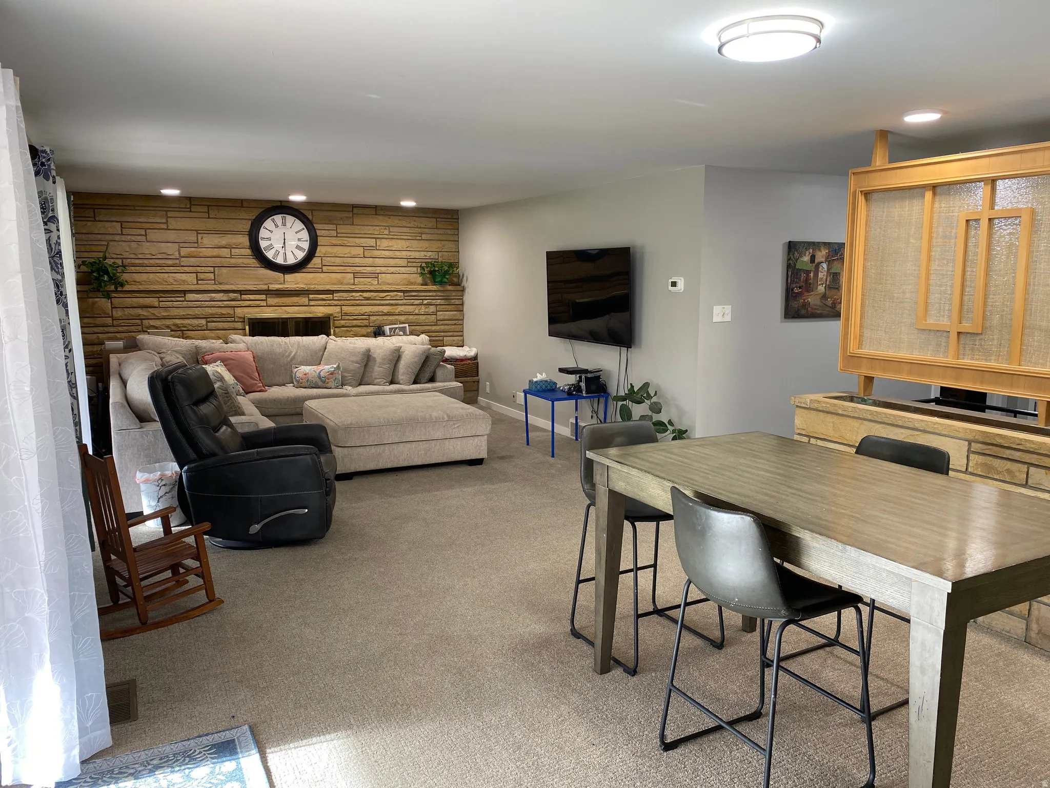 Spacious living area featuring a stacked stone fireplace, recessed lighting, and soft carpet flooring
