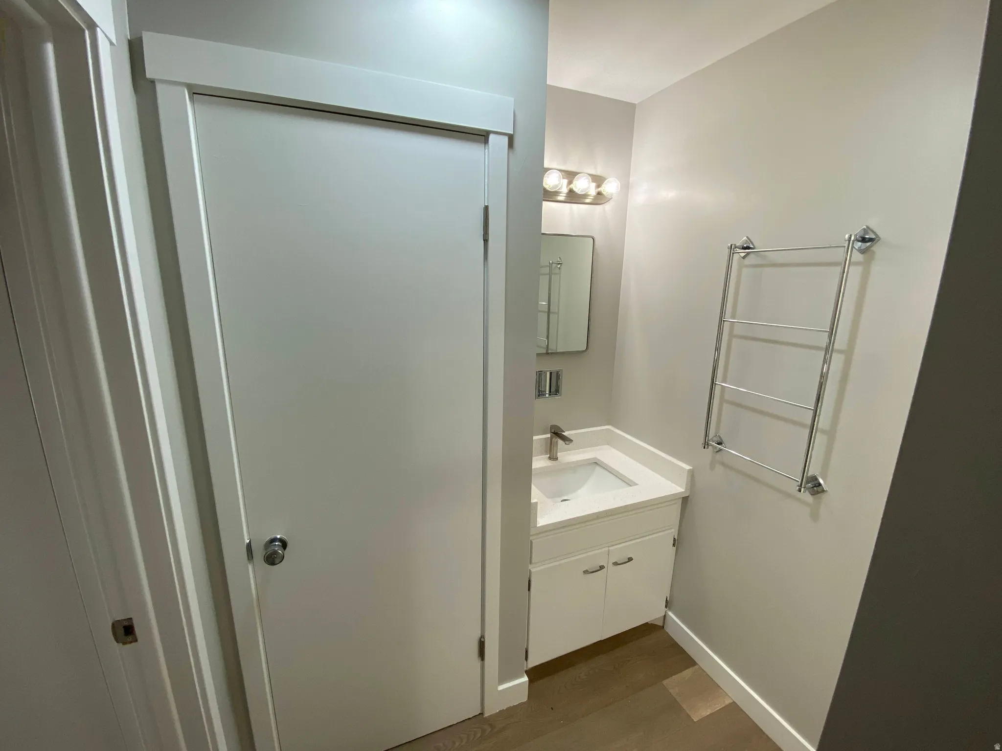 Compact bathroom featuring a white vanity with integrated sink, chrome faucet, and coordinating wall-mounted towel warmer