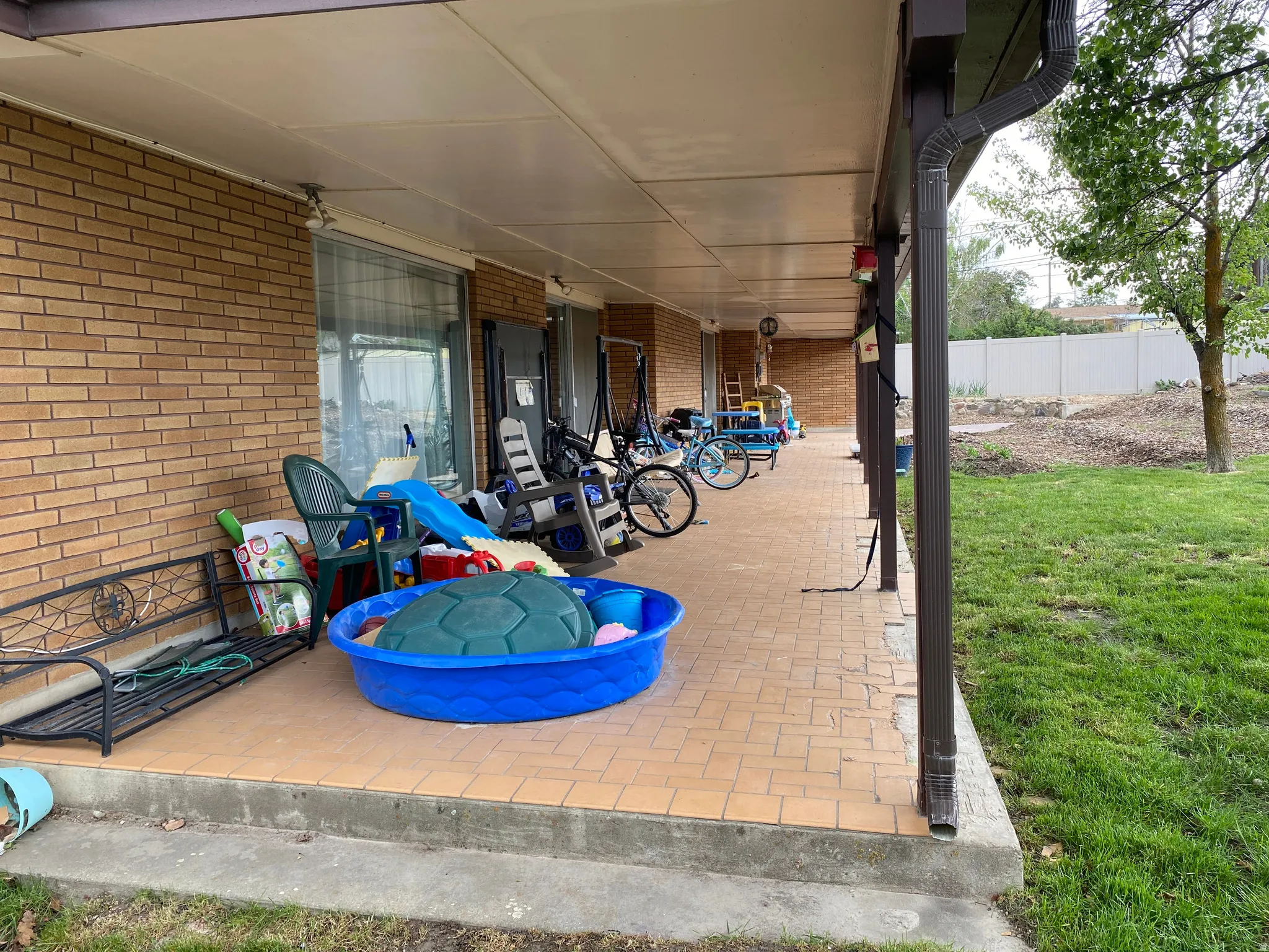 Covered patio featuring a brick exterior and tile flooring