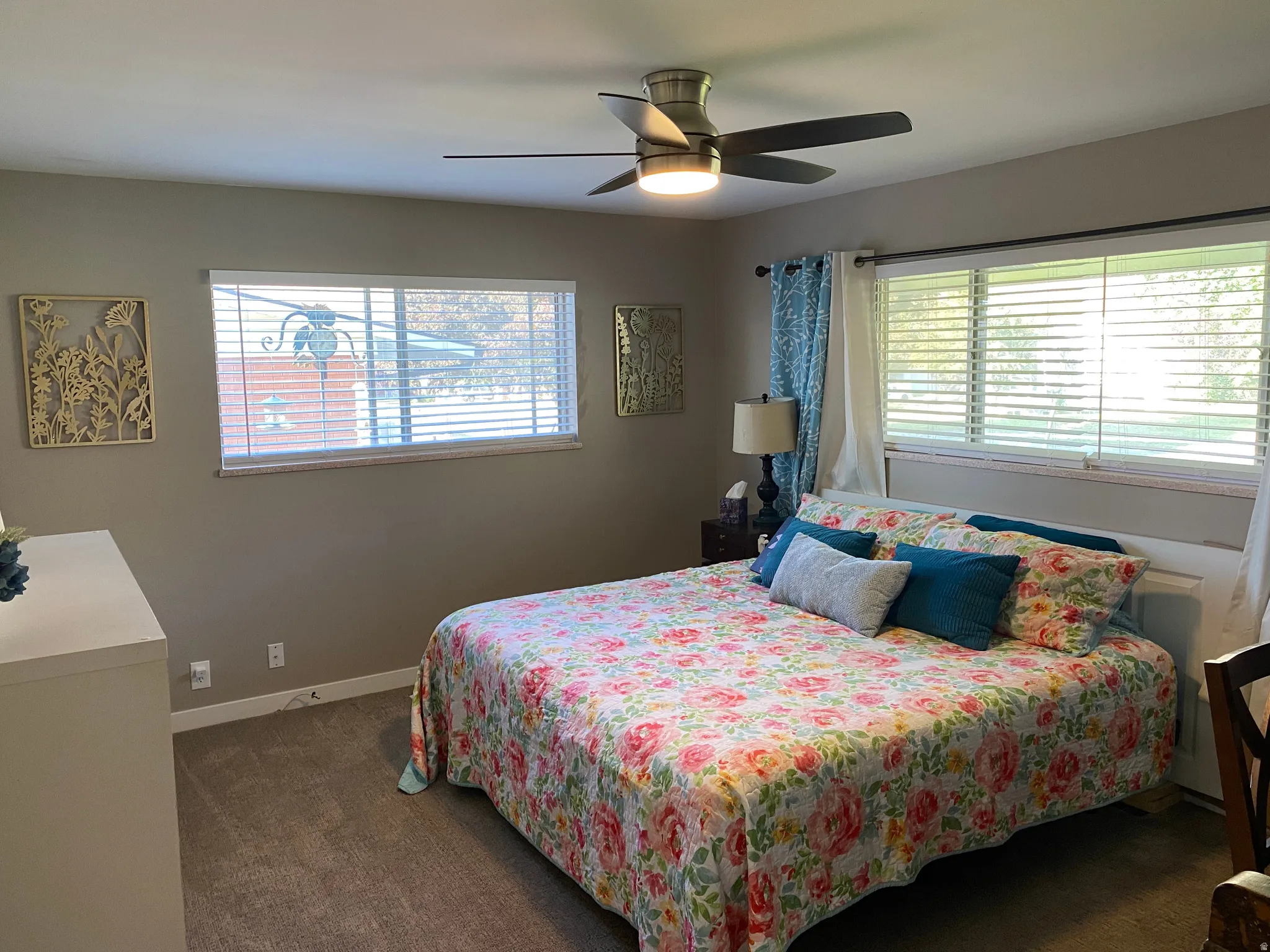 Bedroom featuring neutral wall paint, carpet flooring, a ceiling fan with integrated lighting, and two windows with blinds