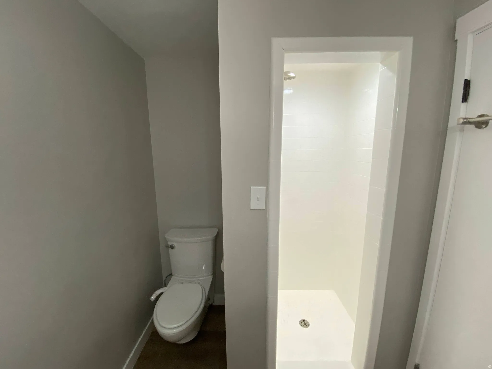 Bathroom featuring a shower stall with white subway tile surround and a contemporary toilet
