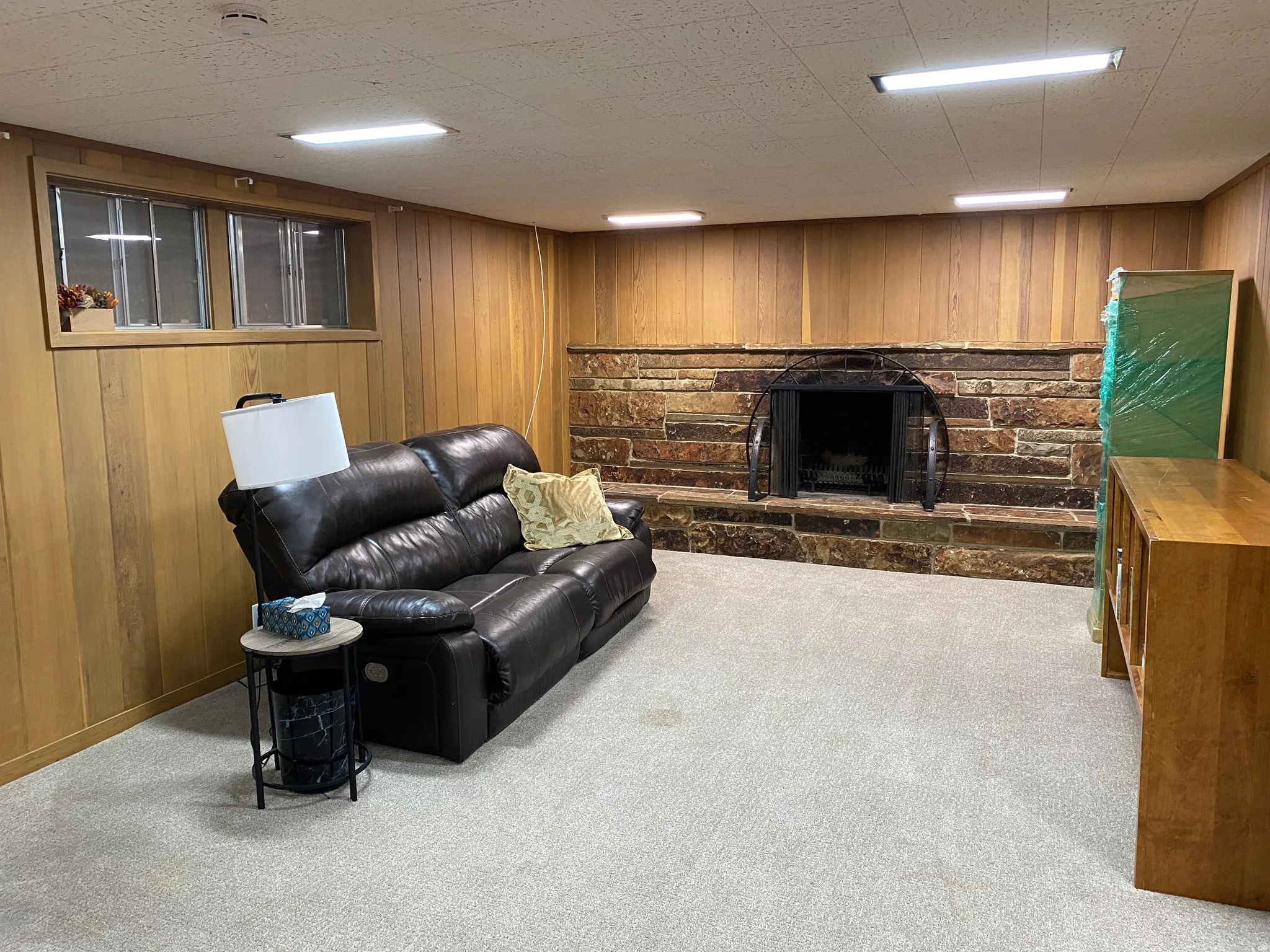 Spacious room featuring light-toned carpeting and wood-paneled walls