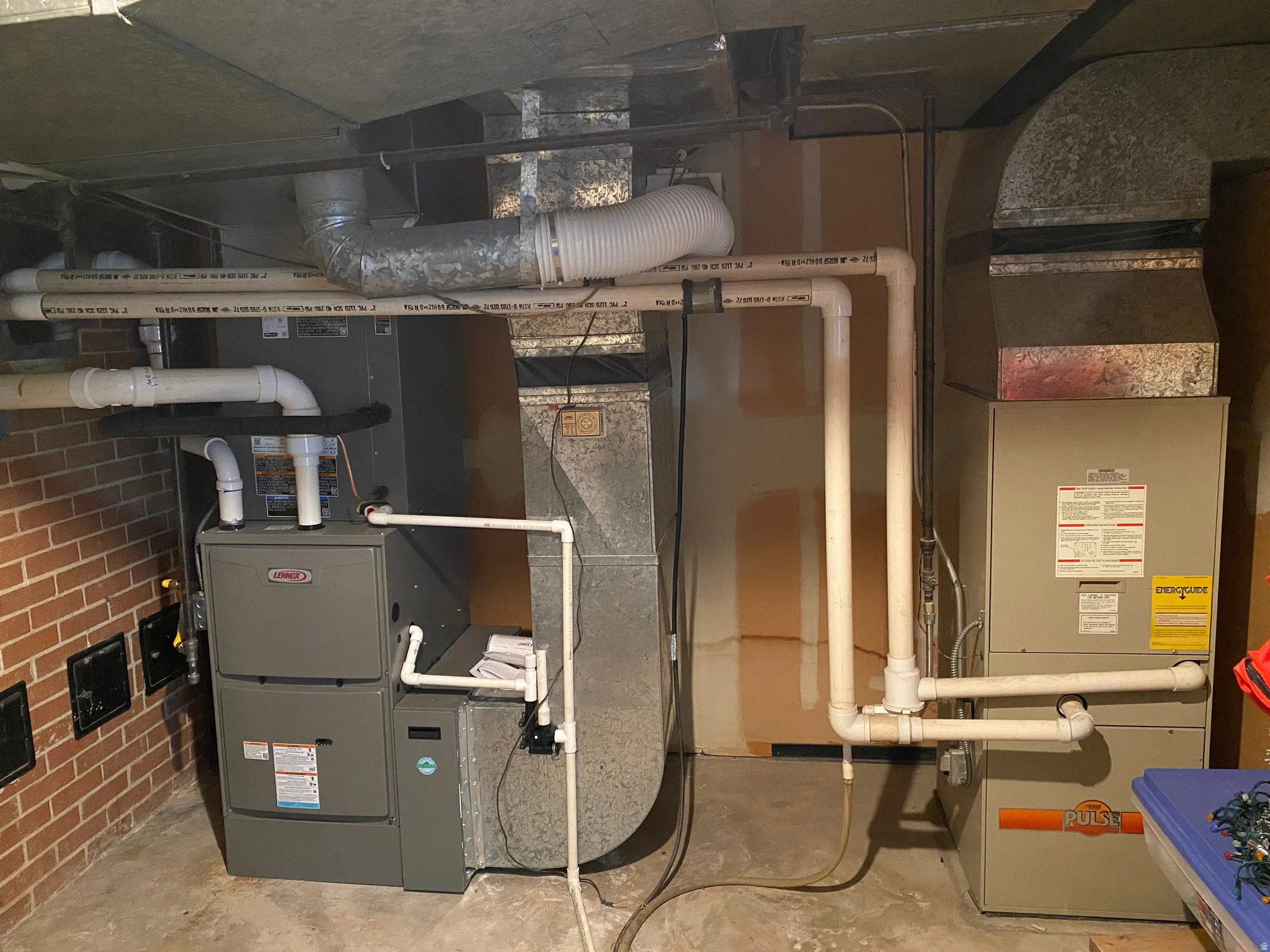 HVAC systems with visible ductwork and piping, concrete flooring, and brick wall elements