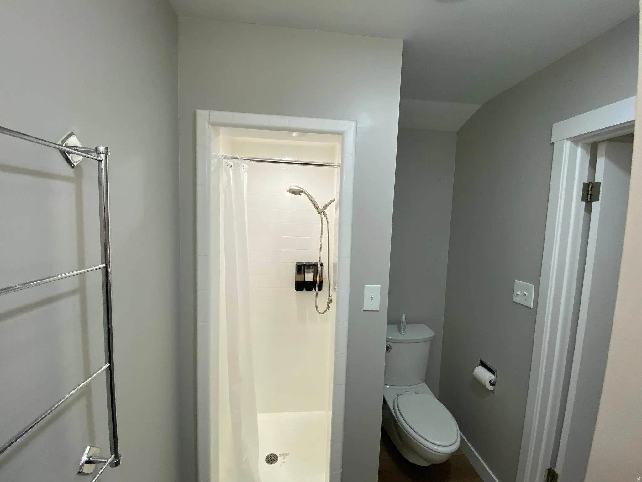 Bathroom featuring a shower stall with a white curtain, a chrome showerhead, and wall-mounted dispensers