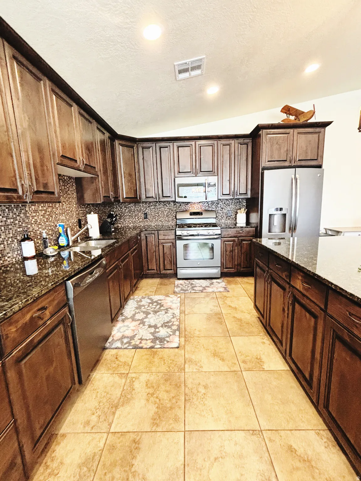 Kitchen featuring extensive dark wood cabinetry, stainless steel appliances, and a mosaic tile backsplash