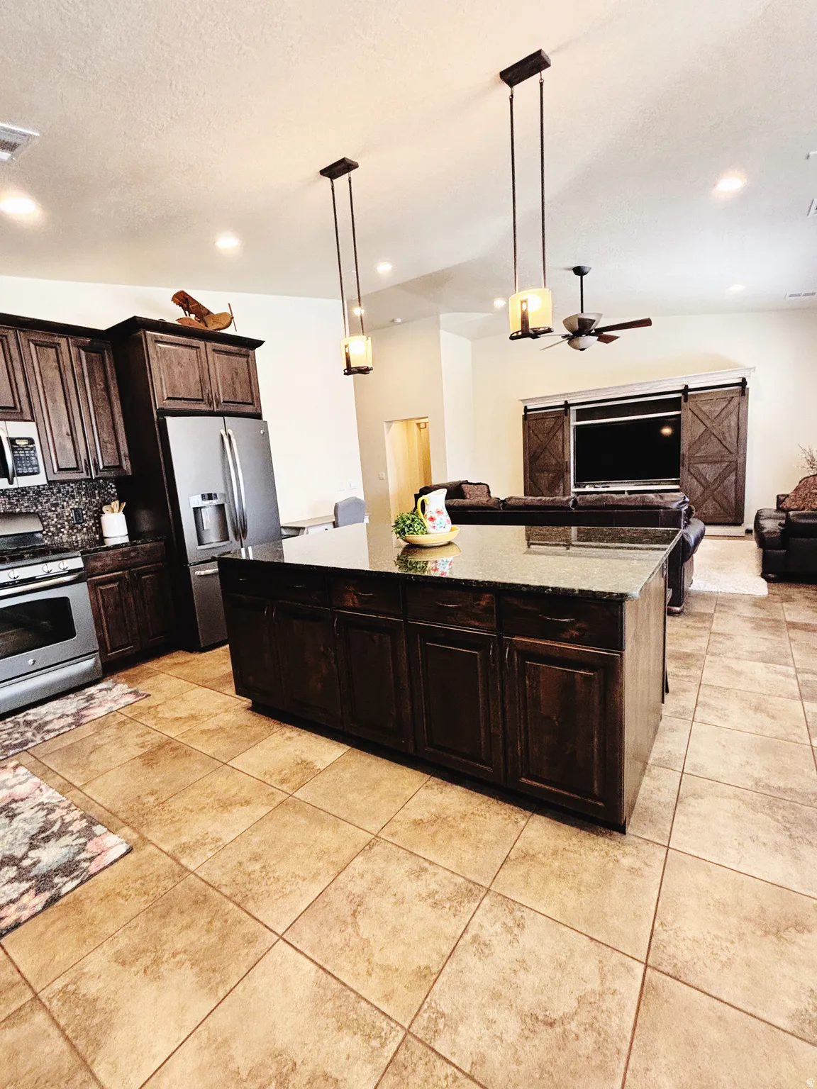 Spacious kitchen island with dark cabinetry and a dark stone countertop