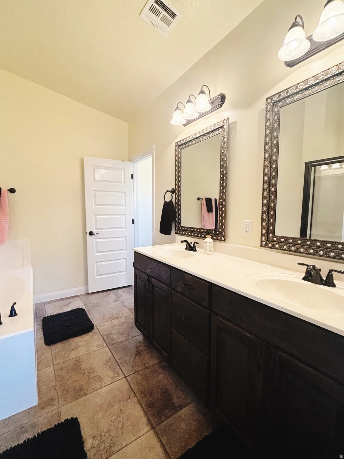 Dual vanity with dark wood-finish cabinetry and white countertops