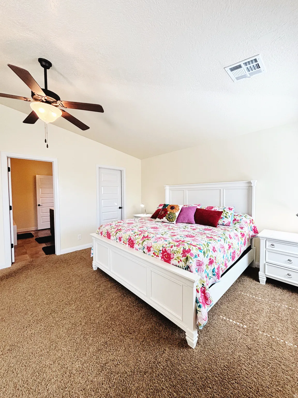 Neutral-toned room featuring a ceiling fan with integrated lighting, textured carpeting, and light-colored walls