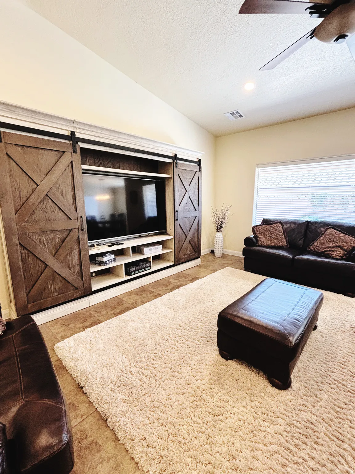 Living area featuring a built-in entertainment center with barn door style closures, recessed lighting, ceiling fan, and tile flooring