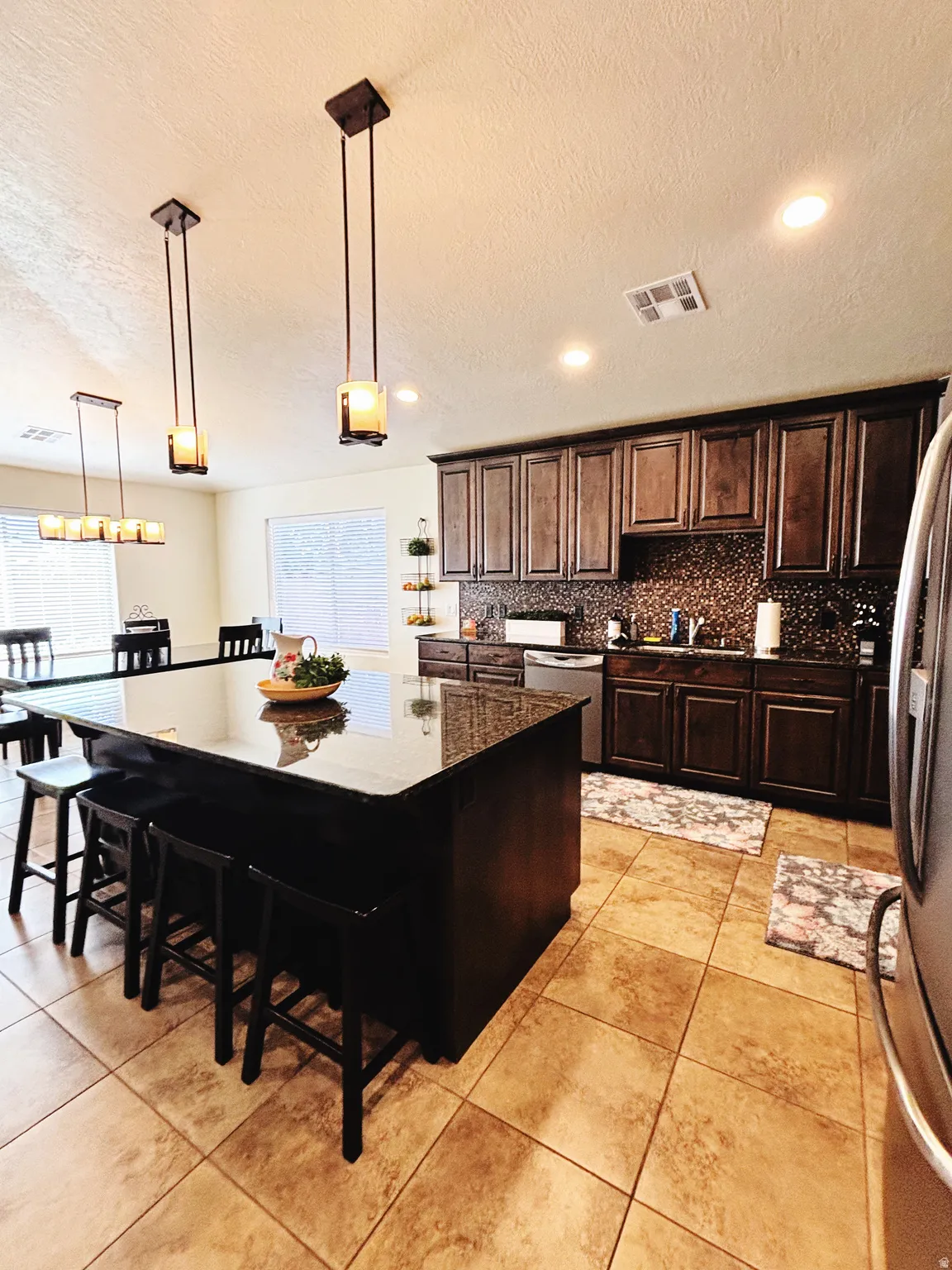 Kitchen featuring dark wood cabinetry, granite countertops, and a mosaic tile backsplash