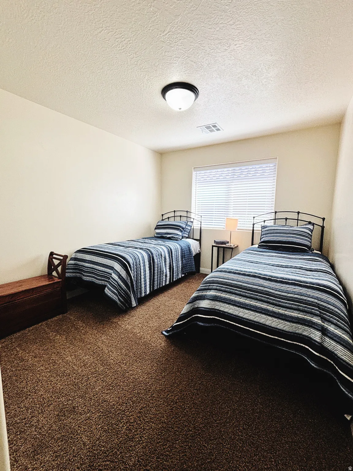Bedroom featuring neutral tone walls, brown shag carpeting, and a window with blinds