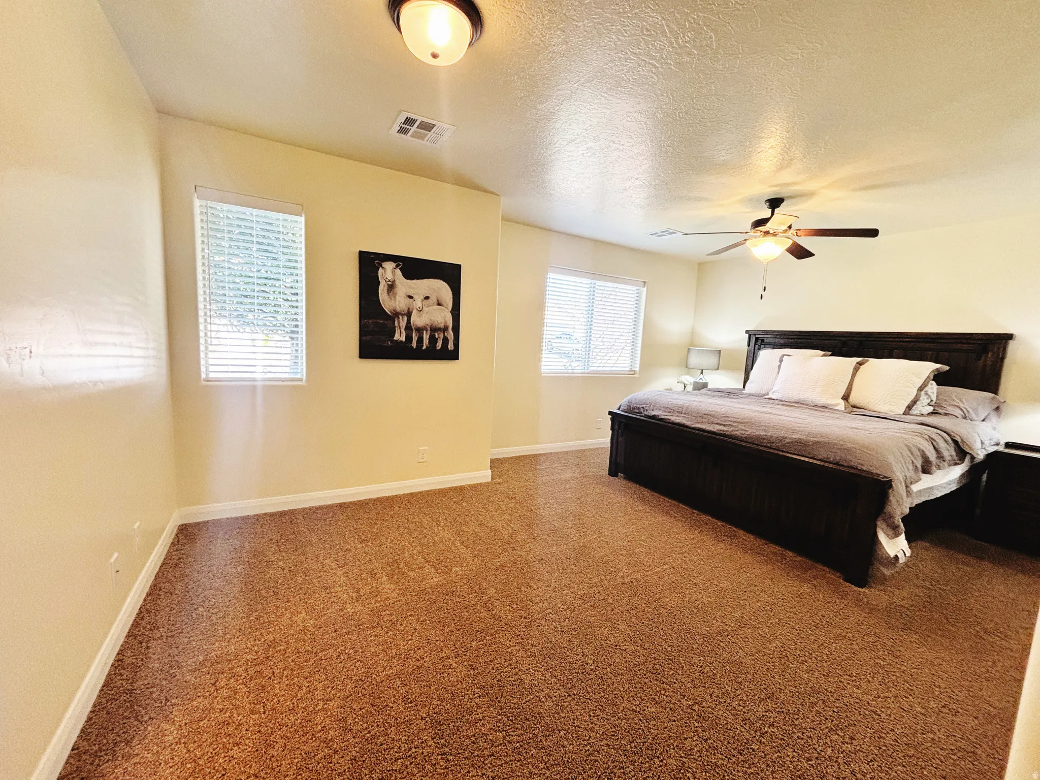 Spacious room featuring neutral-toned walls, textured carpeting, and multiple windows