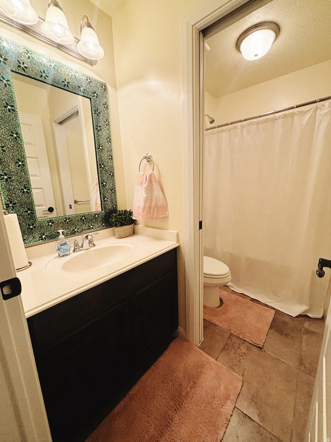 Bathroom featuring a dark vanity with a white countertop, an oval undermount sink, and a decorative tiled mirror frame
