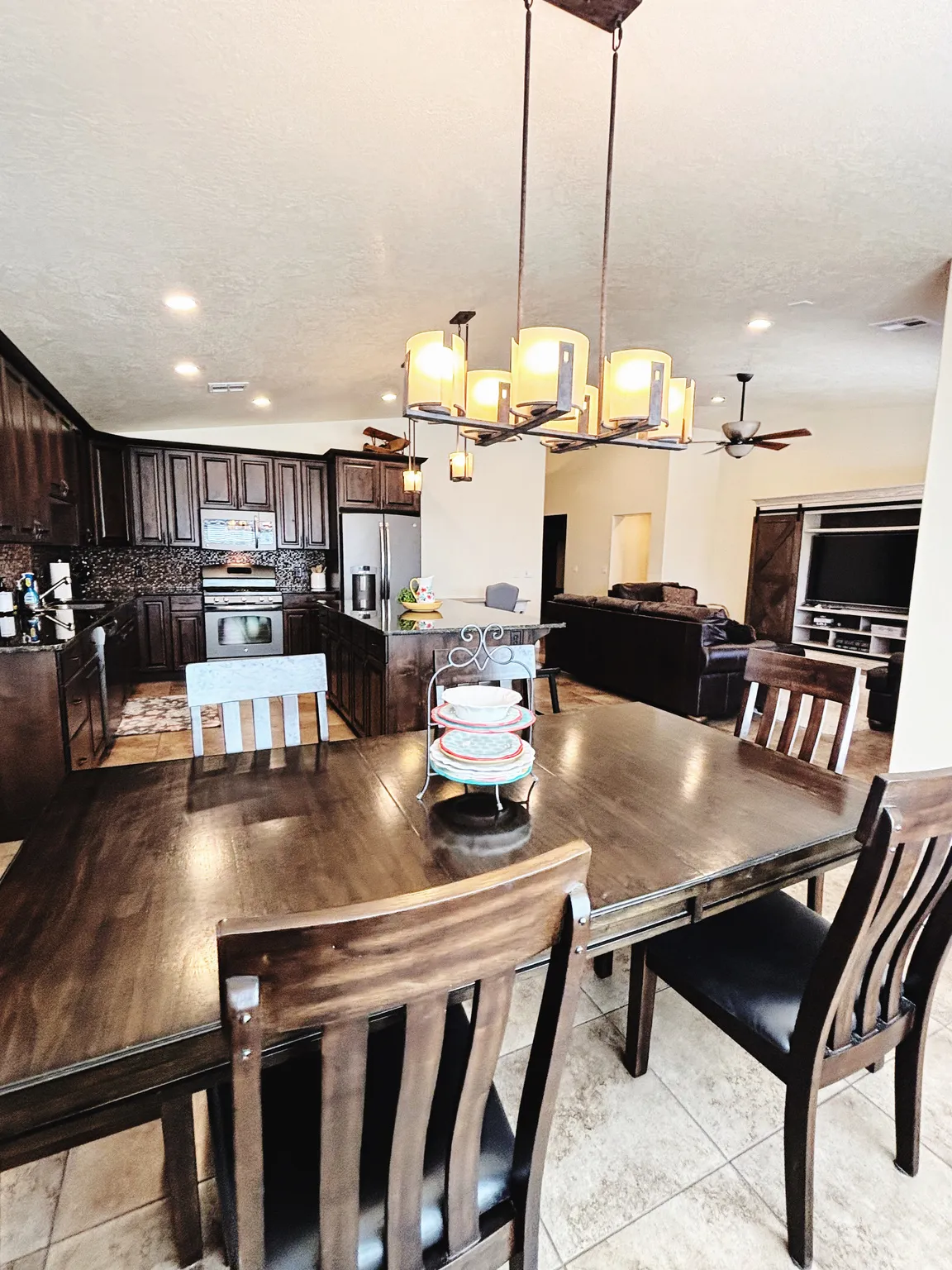 Open-concept living space featuring a dining area with a modern chandelier and tile flooring