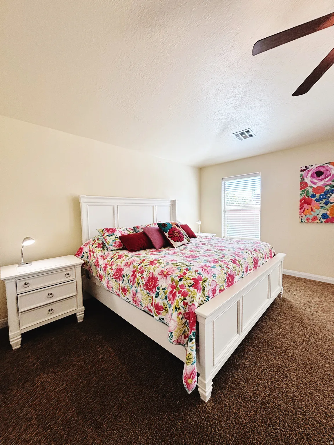 Carpeted bedroom featuring neutral-toned walls, a ceiling fan, and a single window with blinds