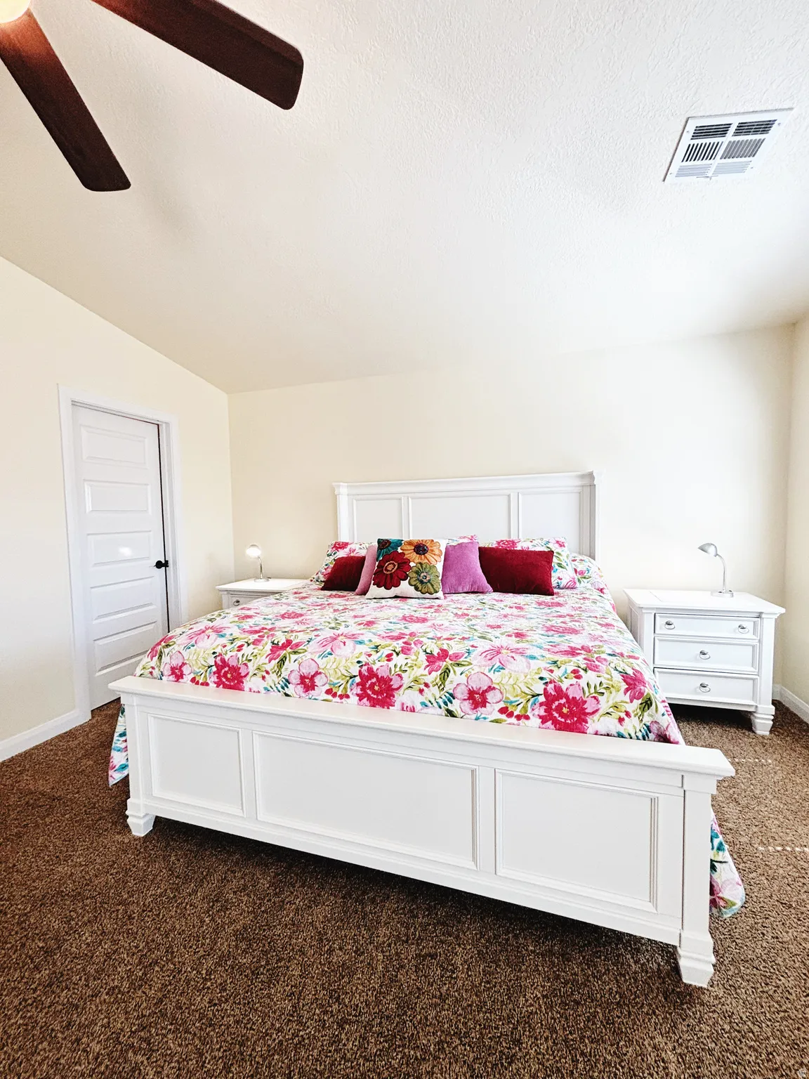 Carpeted room with a ceiling fan, white paneled door, and neutral wall paint