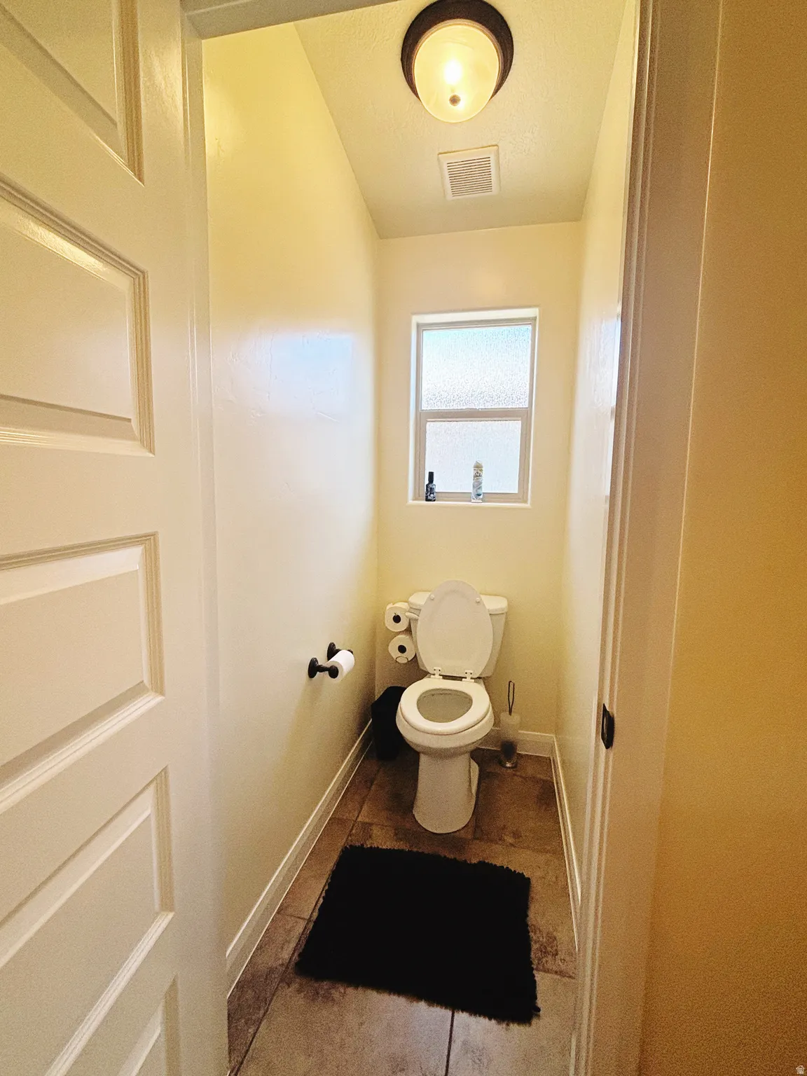 Compact powder room featuring a toilet, frosted window, and recessed lighting