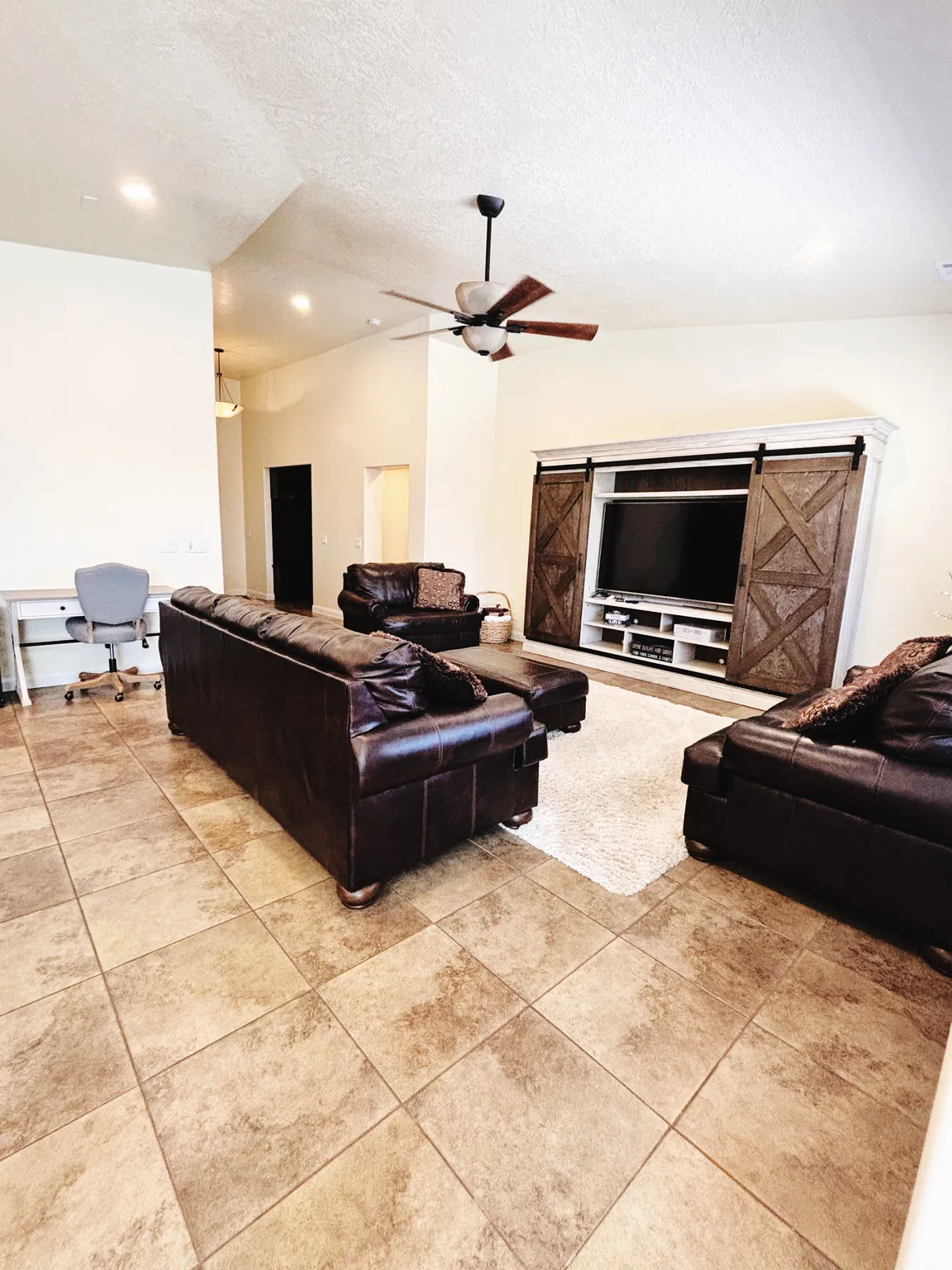 Spacious living area featuring vaulted ceilings, recessed lighting, and large format tile flooring