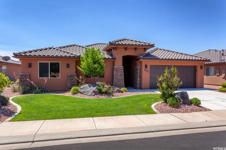 Stucco exterior with stone accents, tile roofing, and an integrated two-car garage