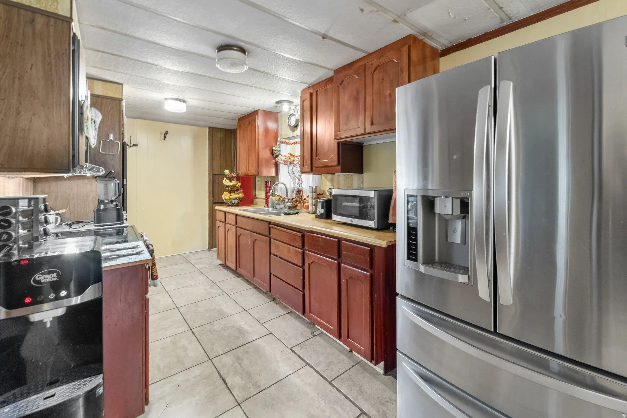 Kitchen featuring recessed panel wood cabinetry, wood-finish countertops, and tile flooring