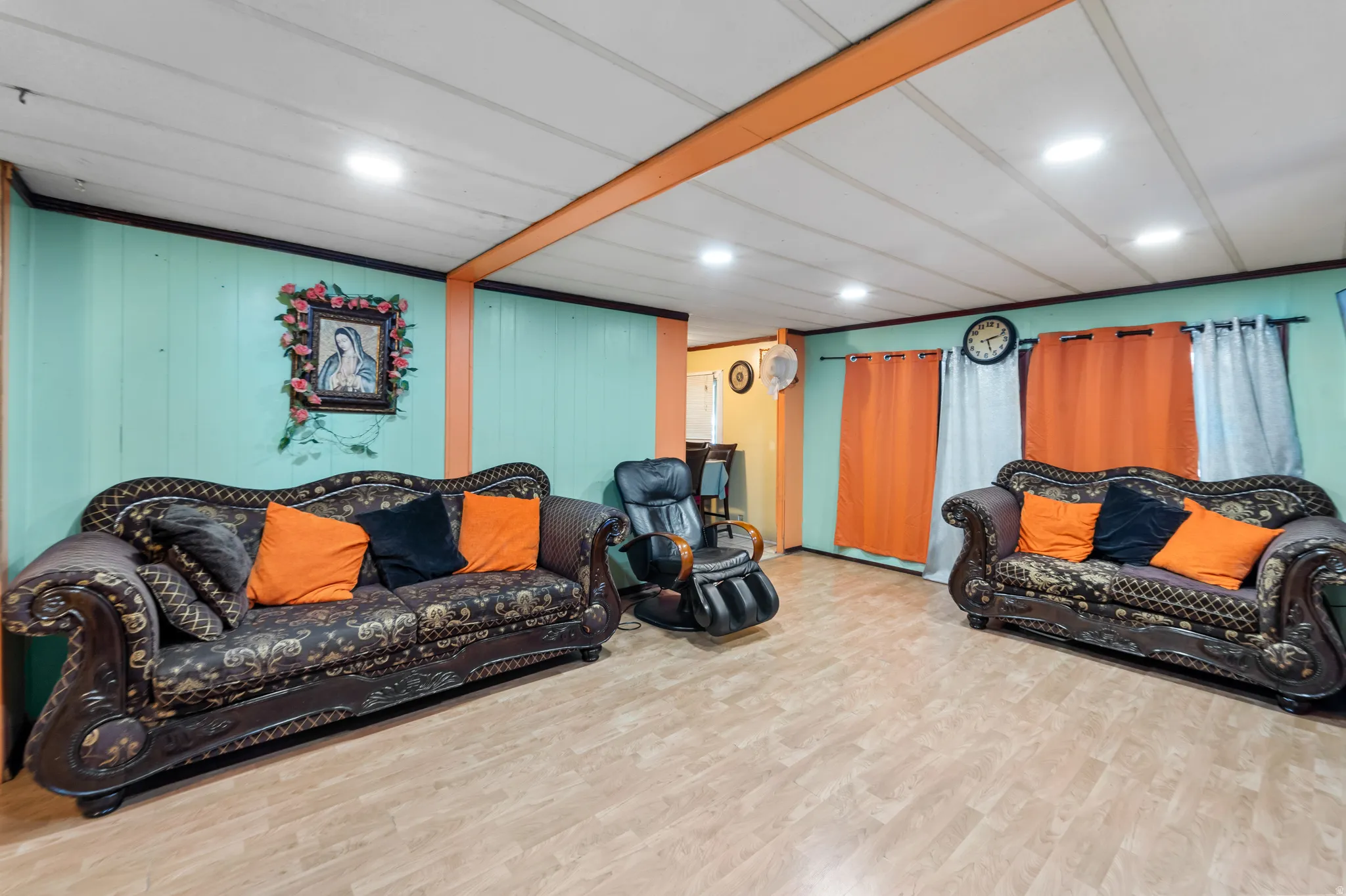 Spacious room featuring wood-finish flooring, light teal wall paneling, and a white ceiling with recessed lighting