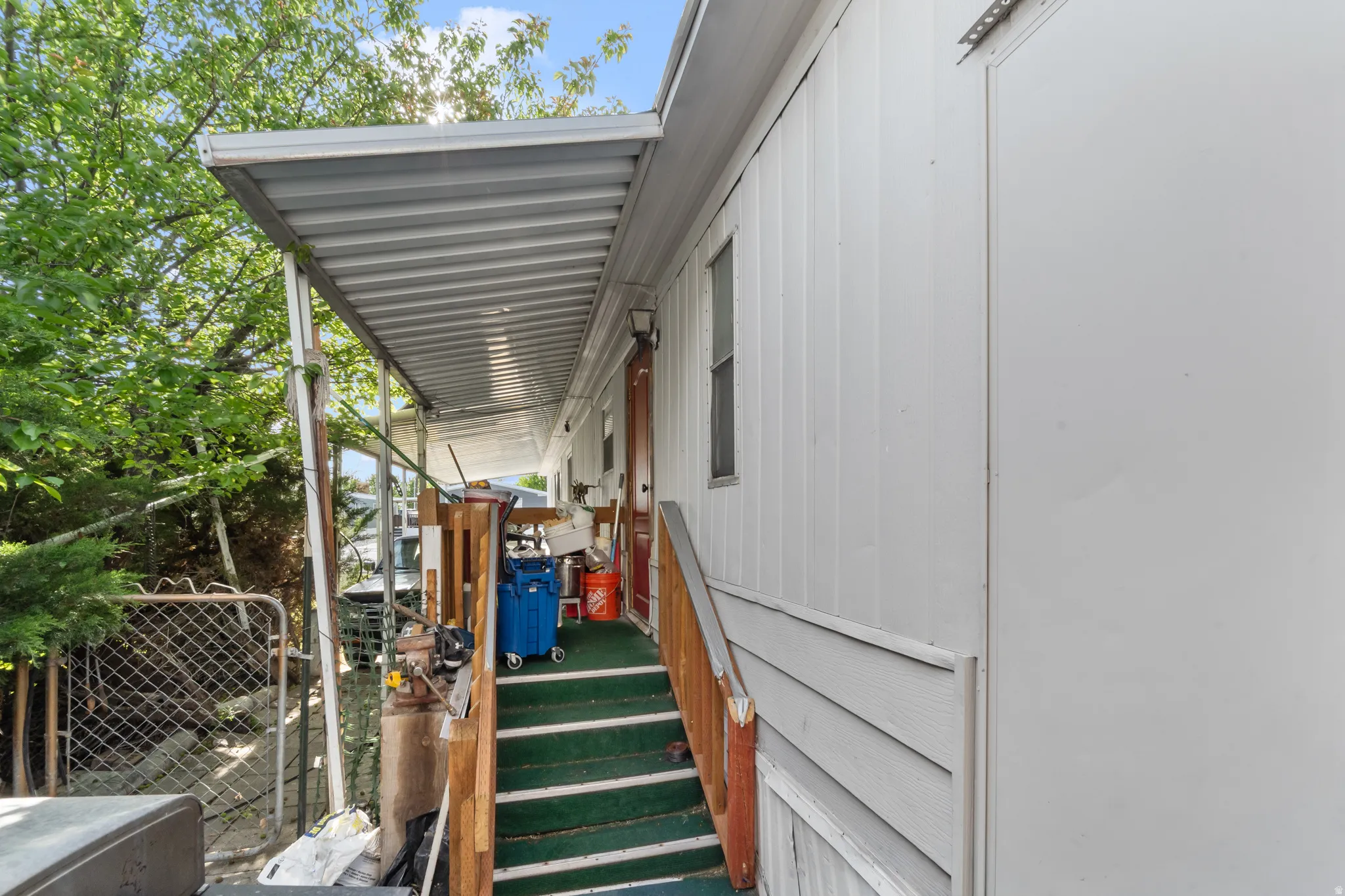 Covered porch with metal roofing, wood railing, and carpeted steps