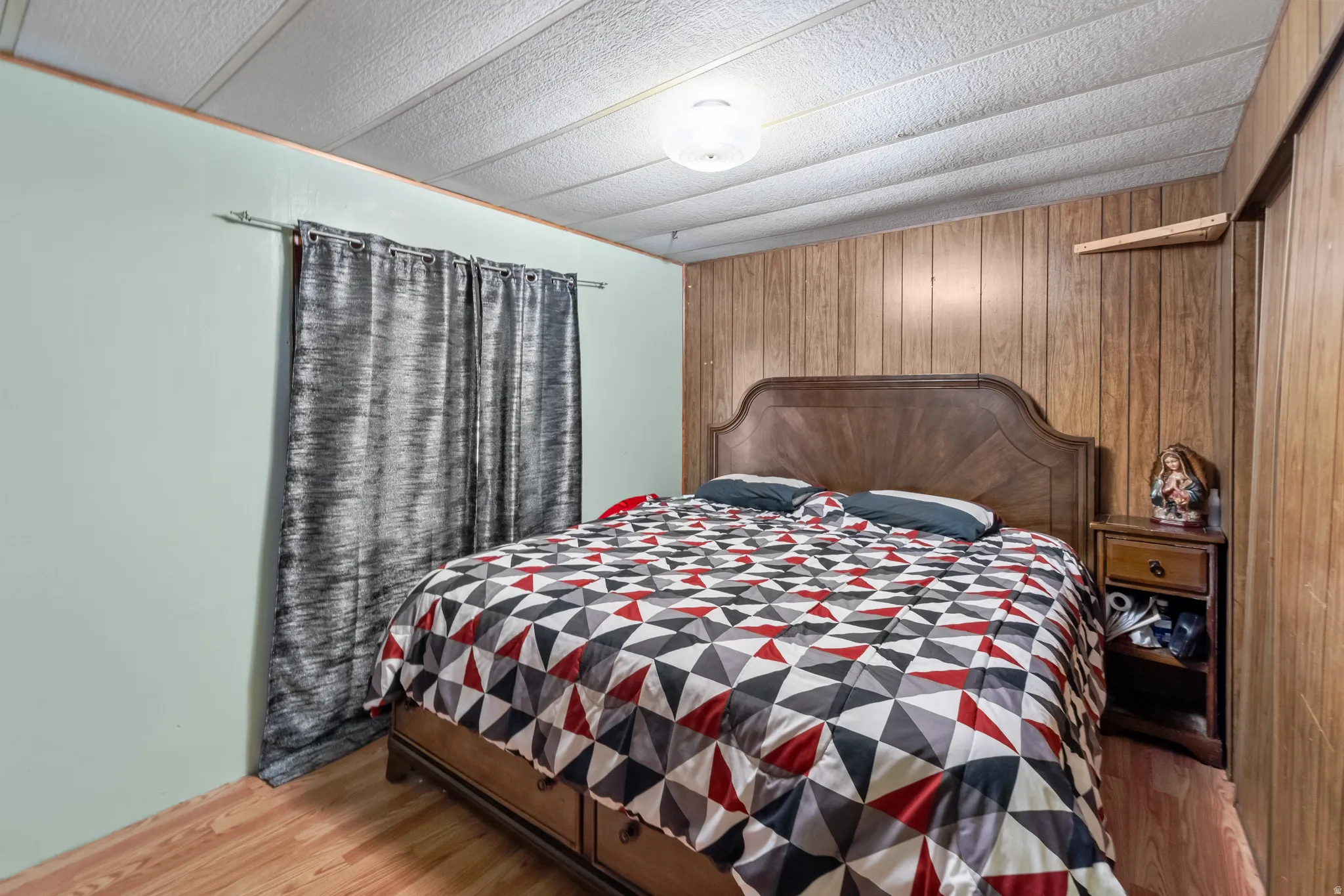 Bedroom featuring wood-finish paneling, light green painted walls, and wood-finish flooring