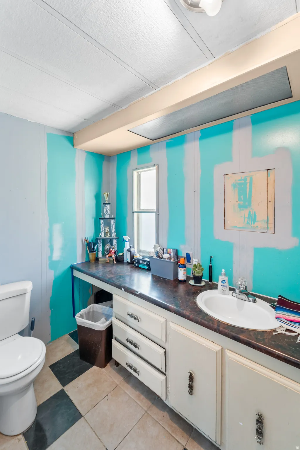 Bathroom featuring a built-in vanity with an integrated sink, checkerboard floor tiling, and a window