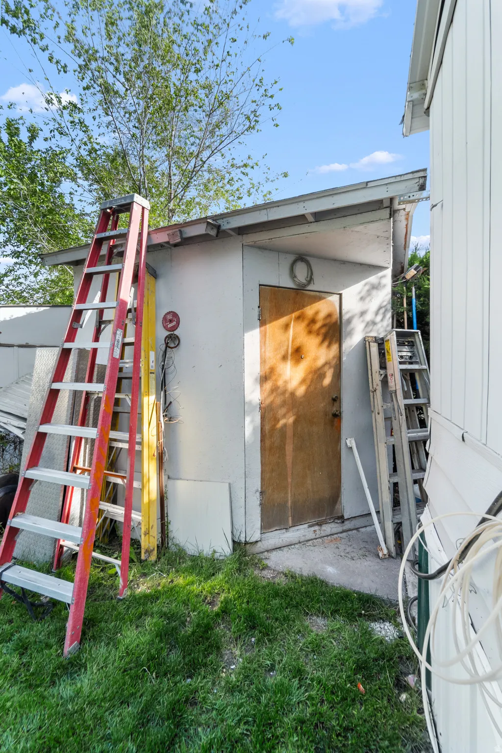Exterior utility building with a wood-finish door, situated on a grassy area