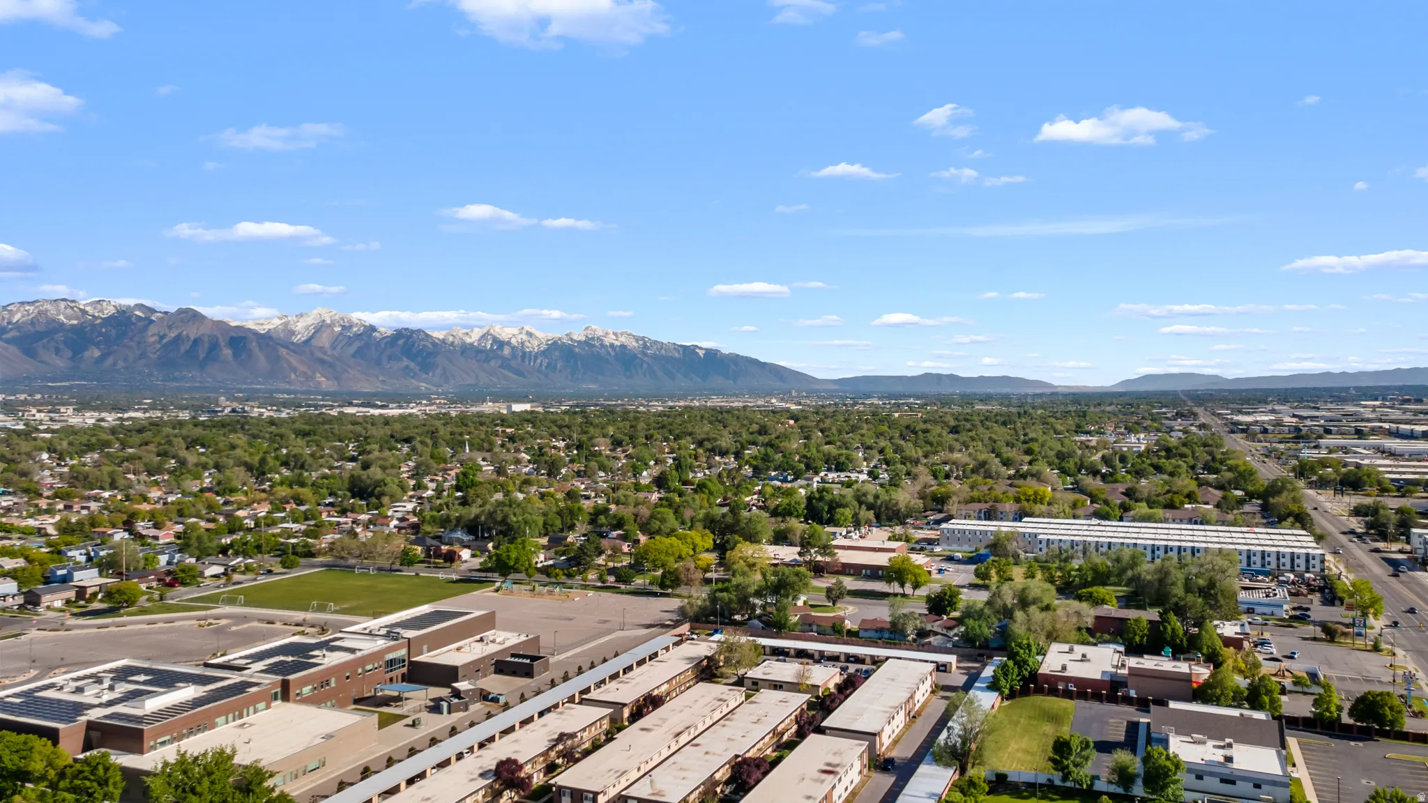 Expansive aerial perspective showcasing a broad urban landscape with distant snow-capped mountains