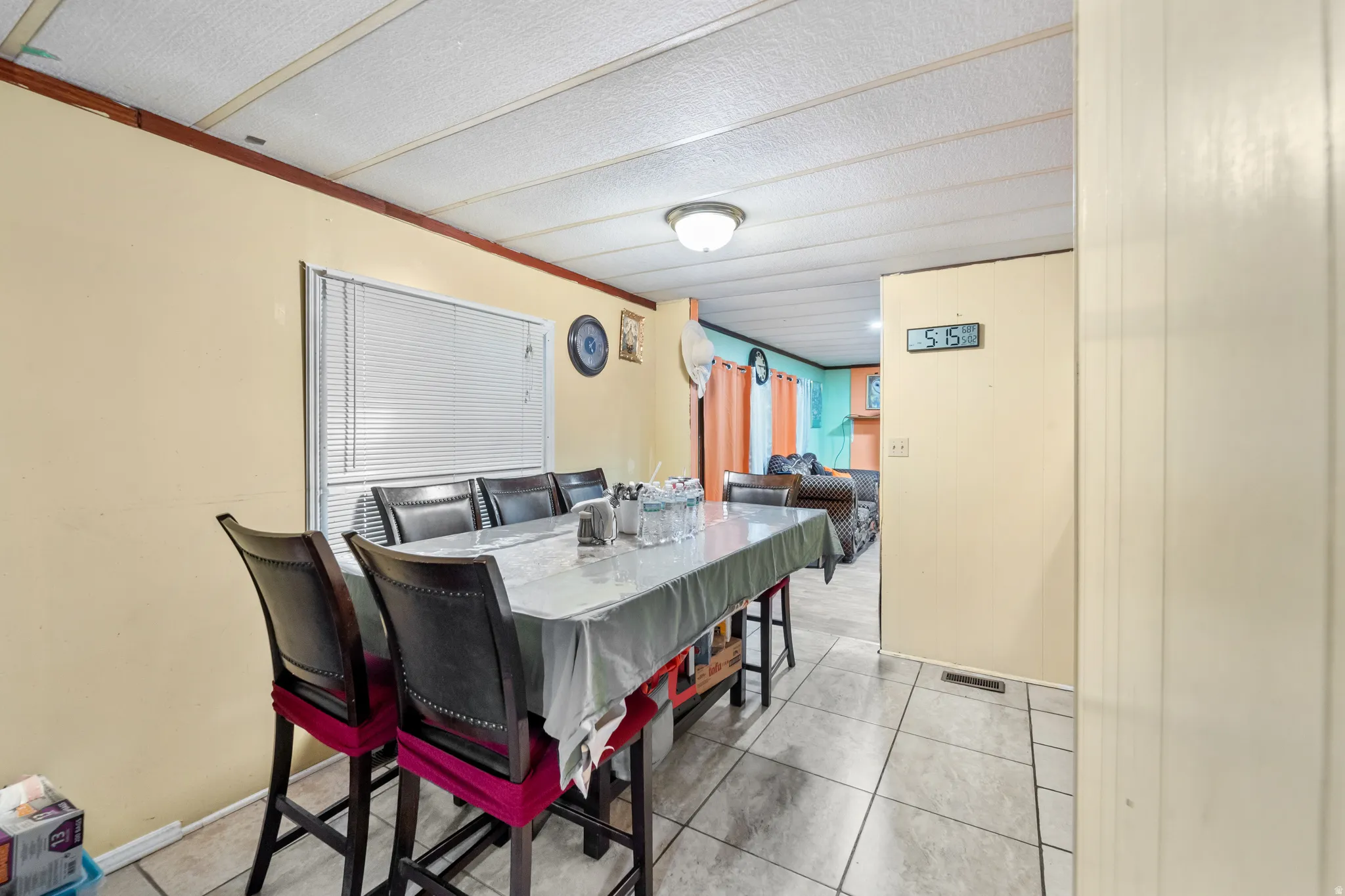 Tiled flooring extends through this room, featuring a window with blinds, light-toned walls, and a panel ceiling