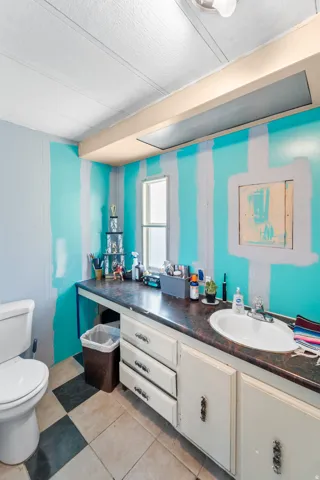 Bathroom featuring a built-in vanity with an integrated sink, checkerboard floor tiling, and a window
