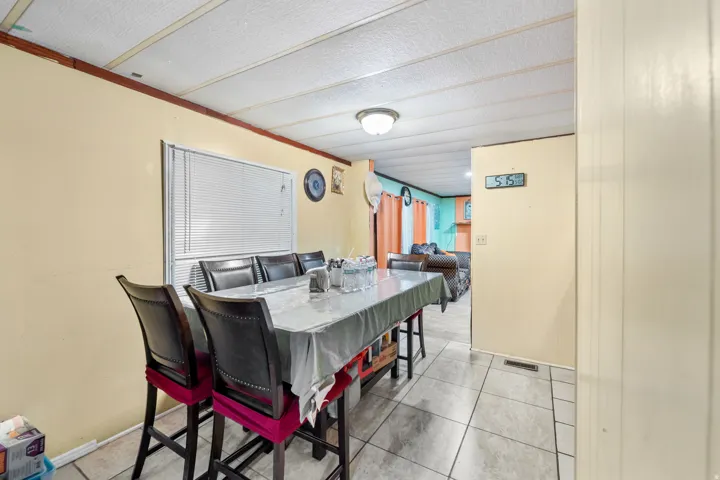 Tiled flooring extends through this room, featuring a window with blinds, light-toned walls, and a panel ceiling