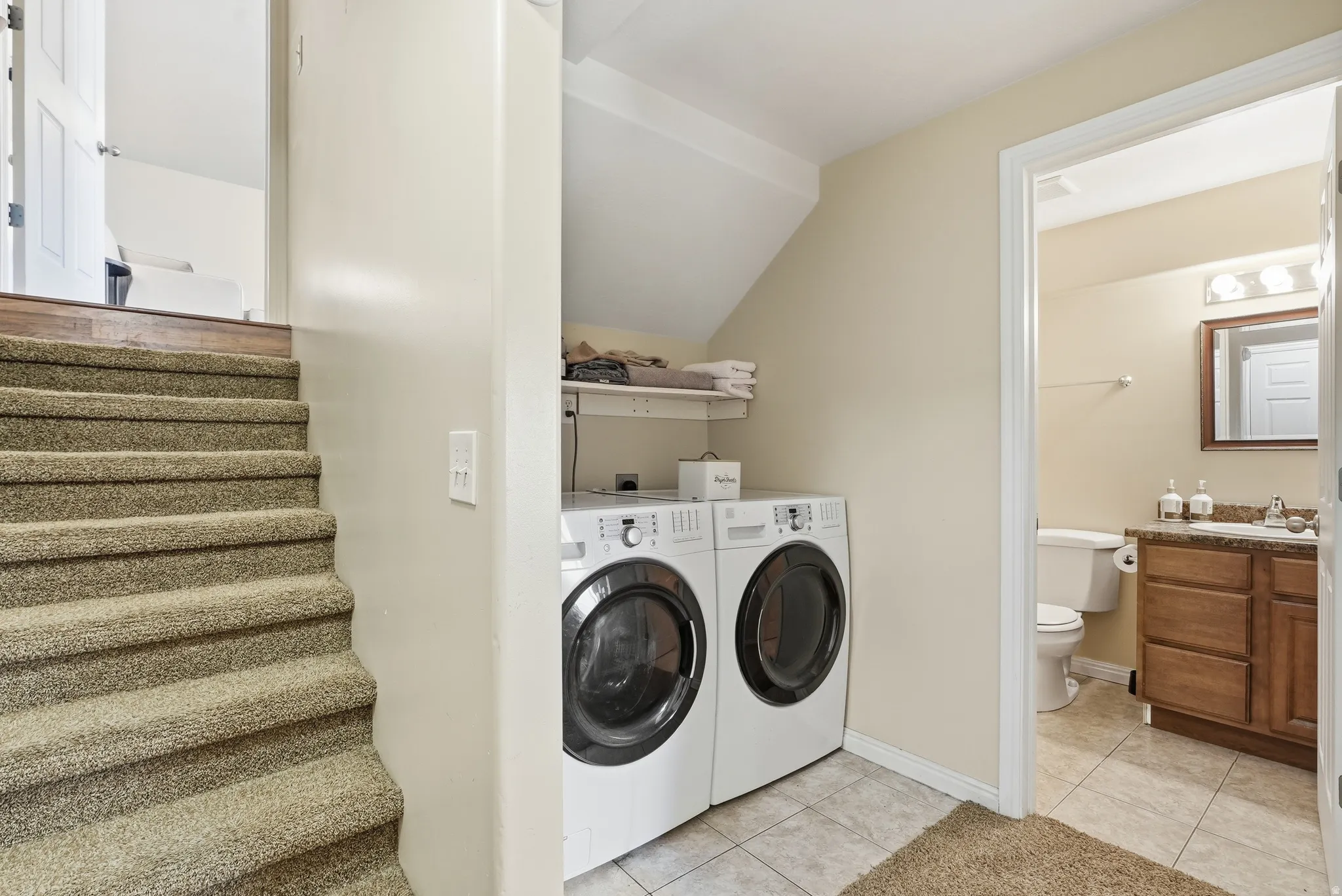Dedicated laundry area featuring front-loading appliances, an overhead shelf, and tile flooring
