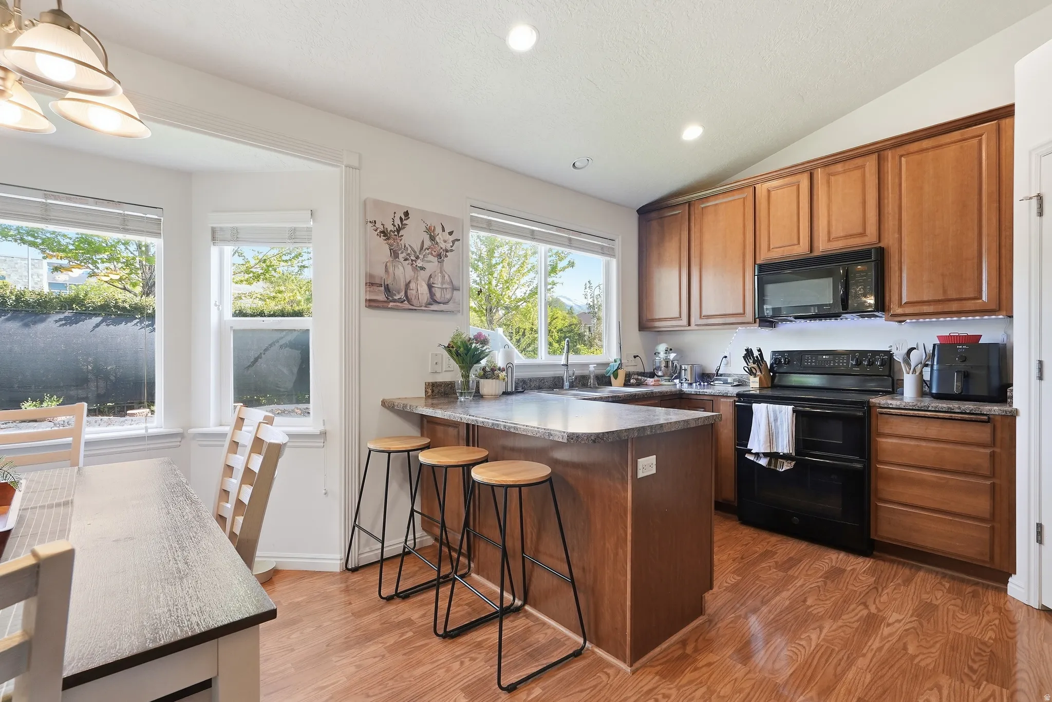 Open-concept kitchen featuring wood-finish flooring, a central island with bar seating, and ample cabinetry