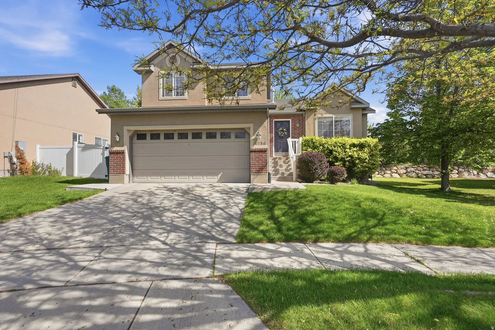 Stucco exterior with brick accents, an integrated two-car garage, and a concrete driveway