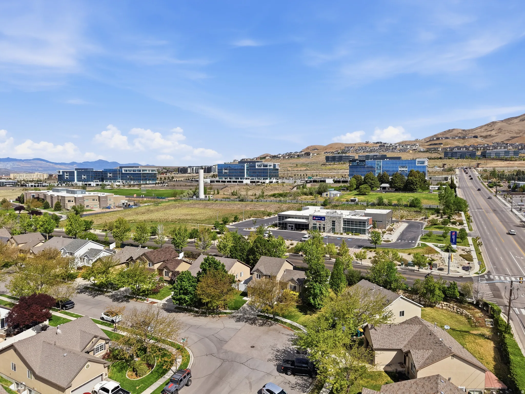 Aerial perspective showcasing a residential neighborhood with a backdrop of commercial buildings and distant mountains