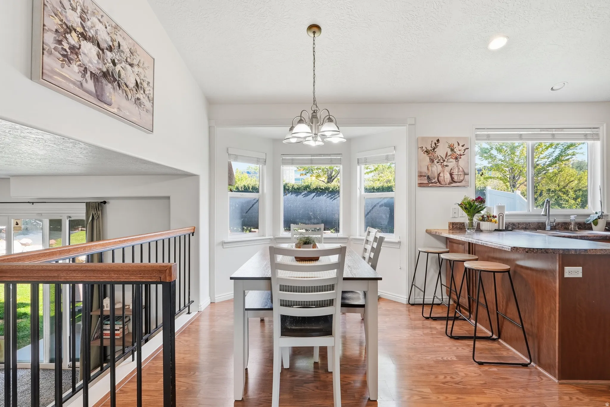 Dining area featuring wood-finish flooring, a bay window, and an overhead chandelier