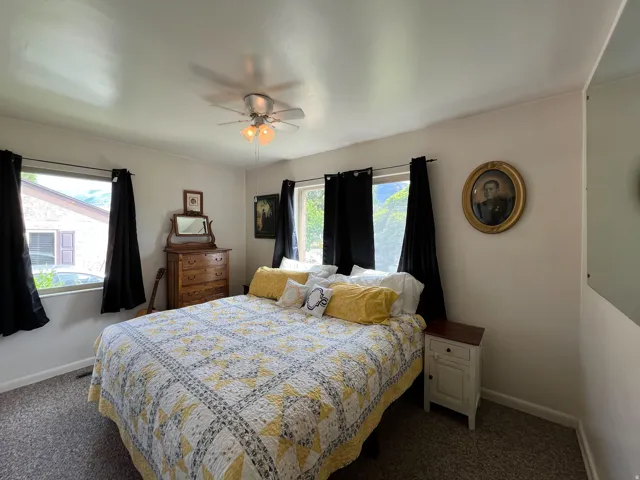 Carpeted bedroom featuring a ceiling fan